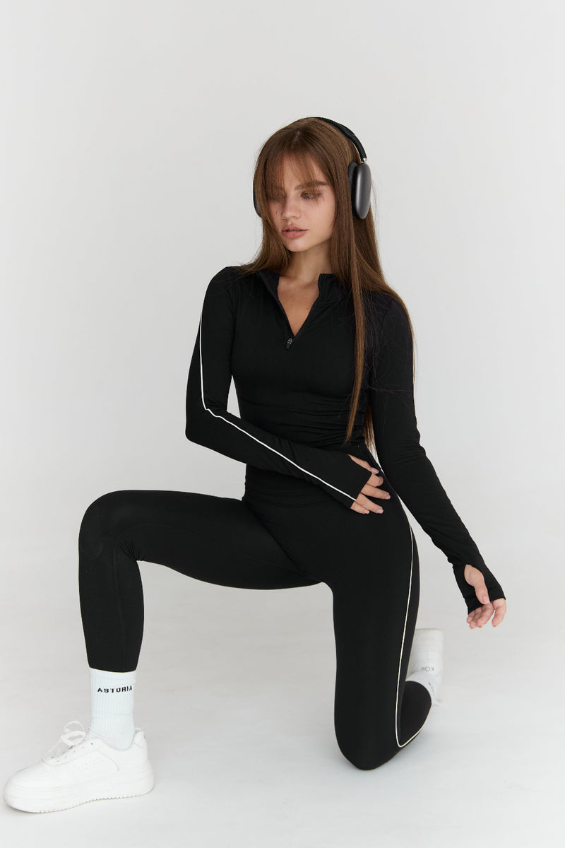 Person wearing a black outfit with white accents on a white background
