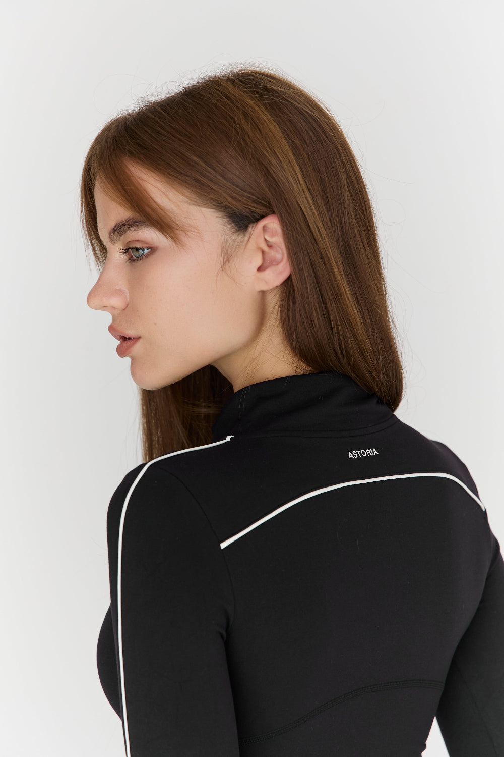 Woman wearing a black jacket with a visible brand logo on a white background
