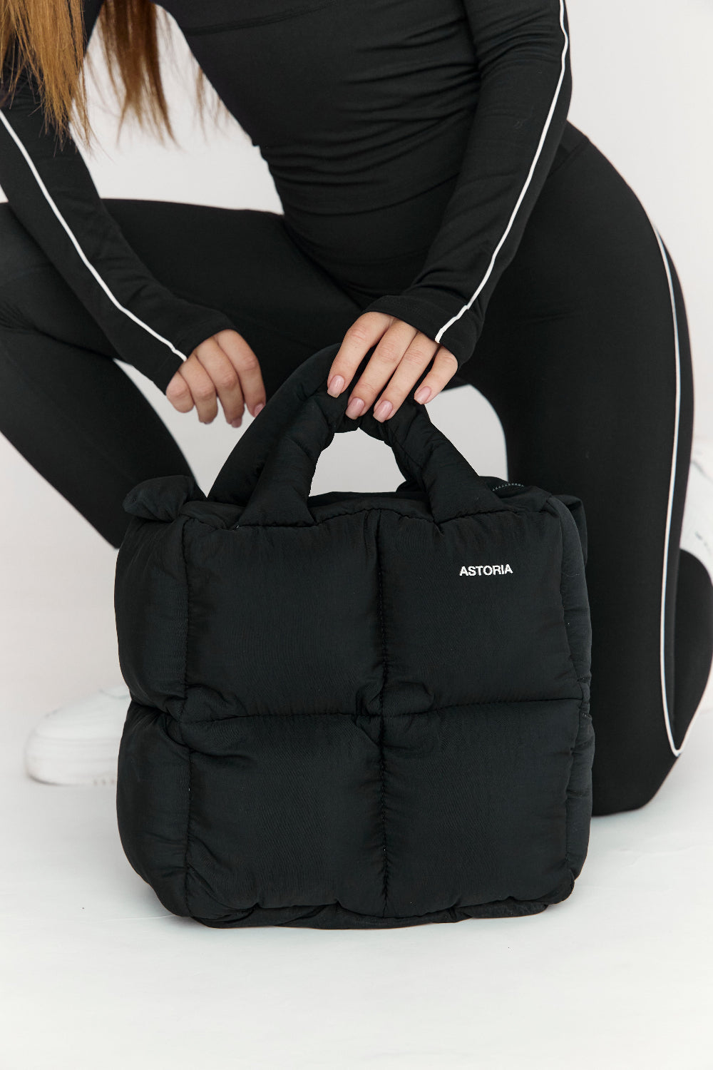 Person holding a black bag with &