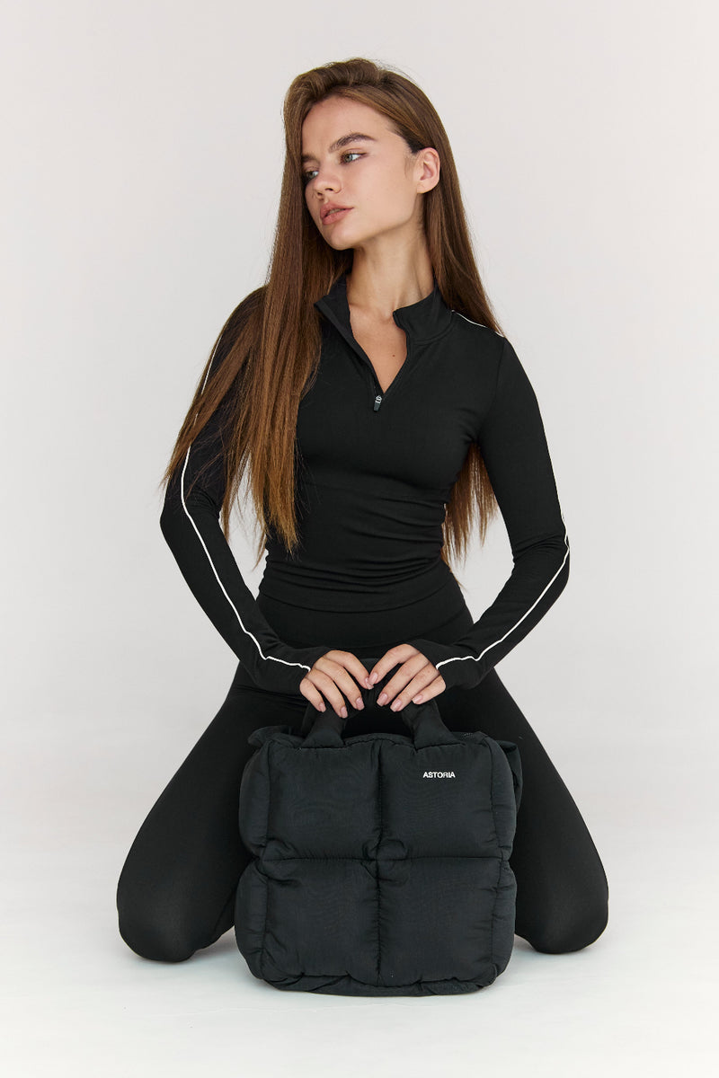Woman holding a black backpack with a plain background