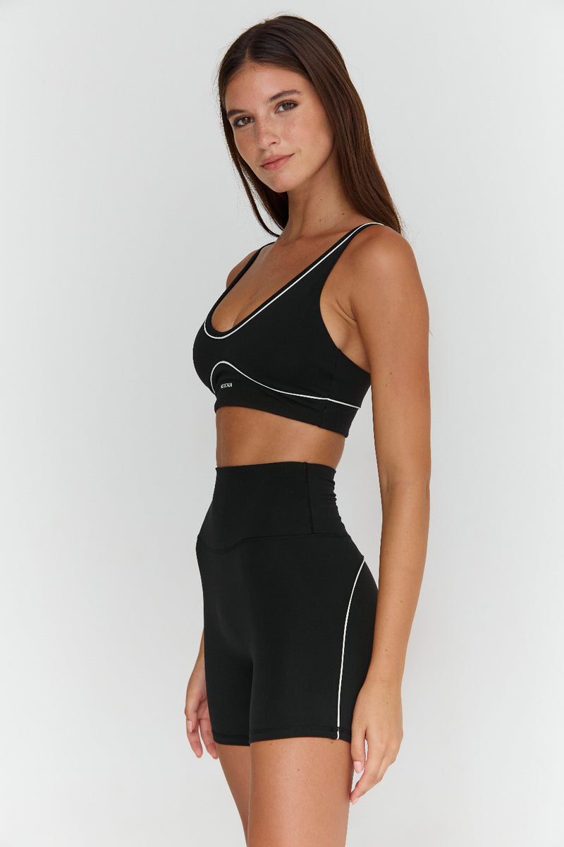 Woman wearing a black sports bra and shorts set on a white background