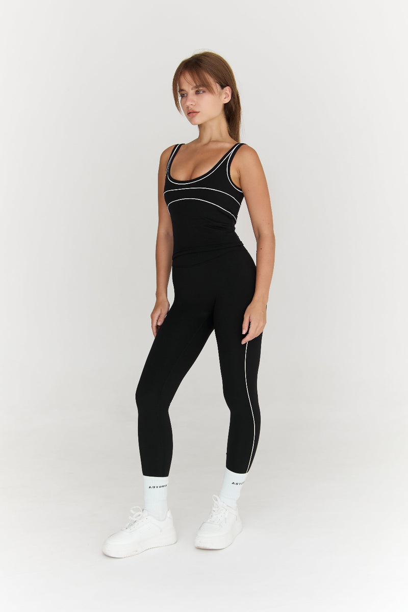 Woman wearing a black athletic outfit with white accents on a white background