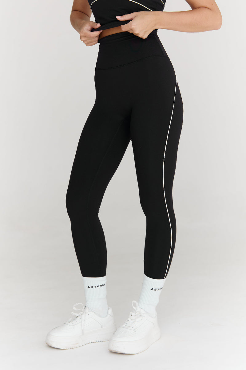 Person wearing black leggings with white accents on a white background