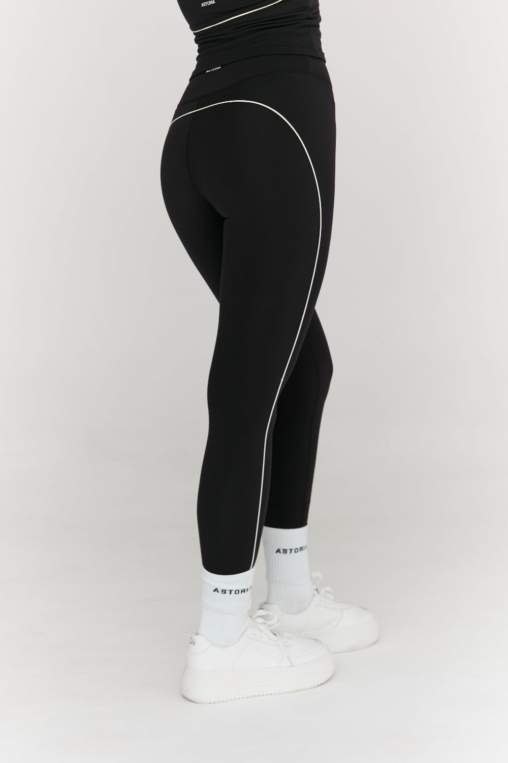 Black leggings with white piping worn by a person on a white background